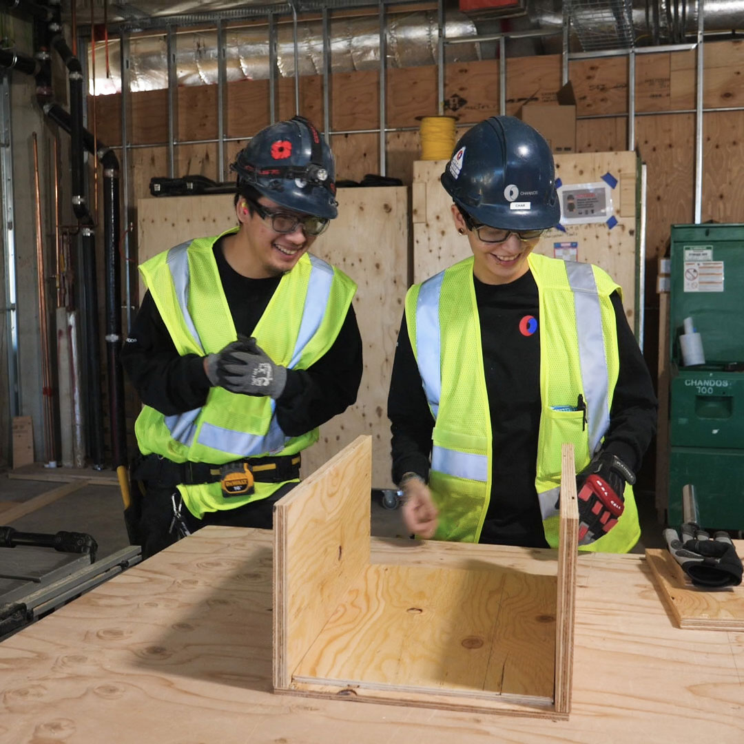 Two workers building something out of plywood