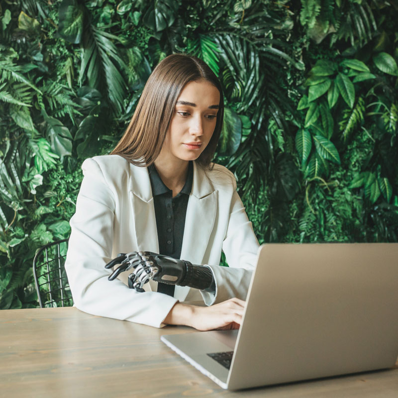 A women working on a computer. She has a prosthetic arm