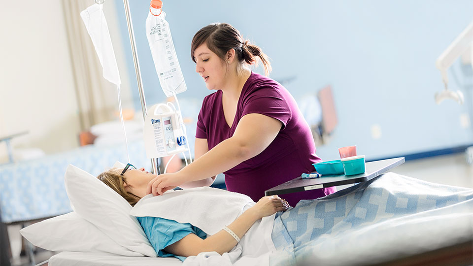 A health care aide adjusting a patient