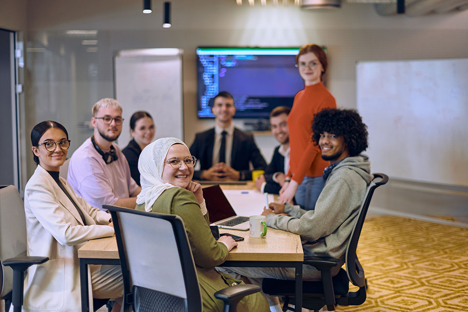 A diverse team of business experts in a modern glass office, attentively listening to a colleague's presentation, fostering collaboration and innovation.