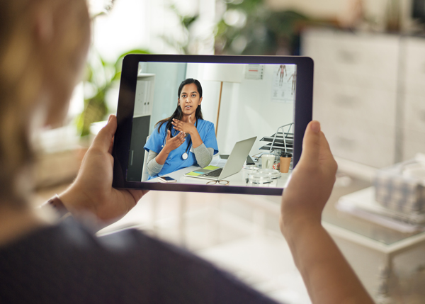 A student holding a tablet who is watching an online nursing course