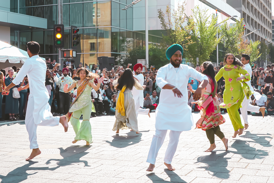 A group of dancers dancing in the street in front of a crowd