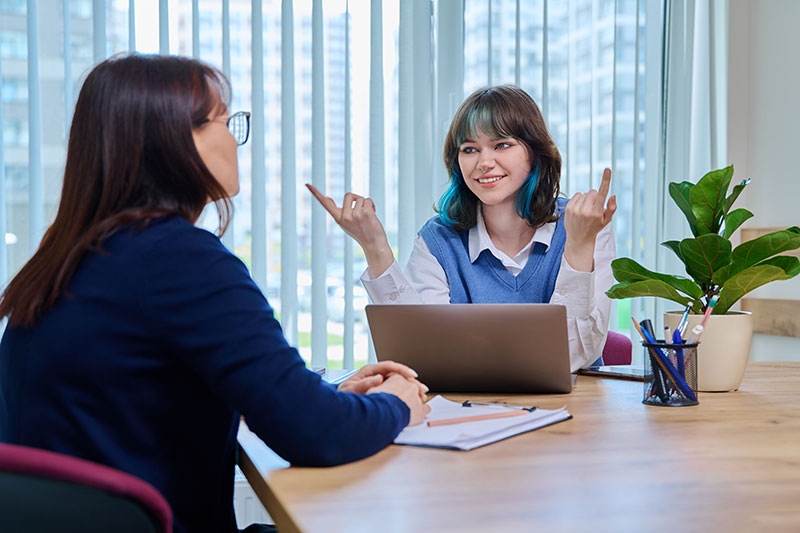 Two women sitting at a table, one has a laptop in front of her